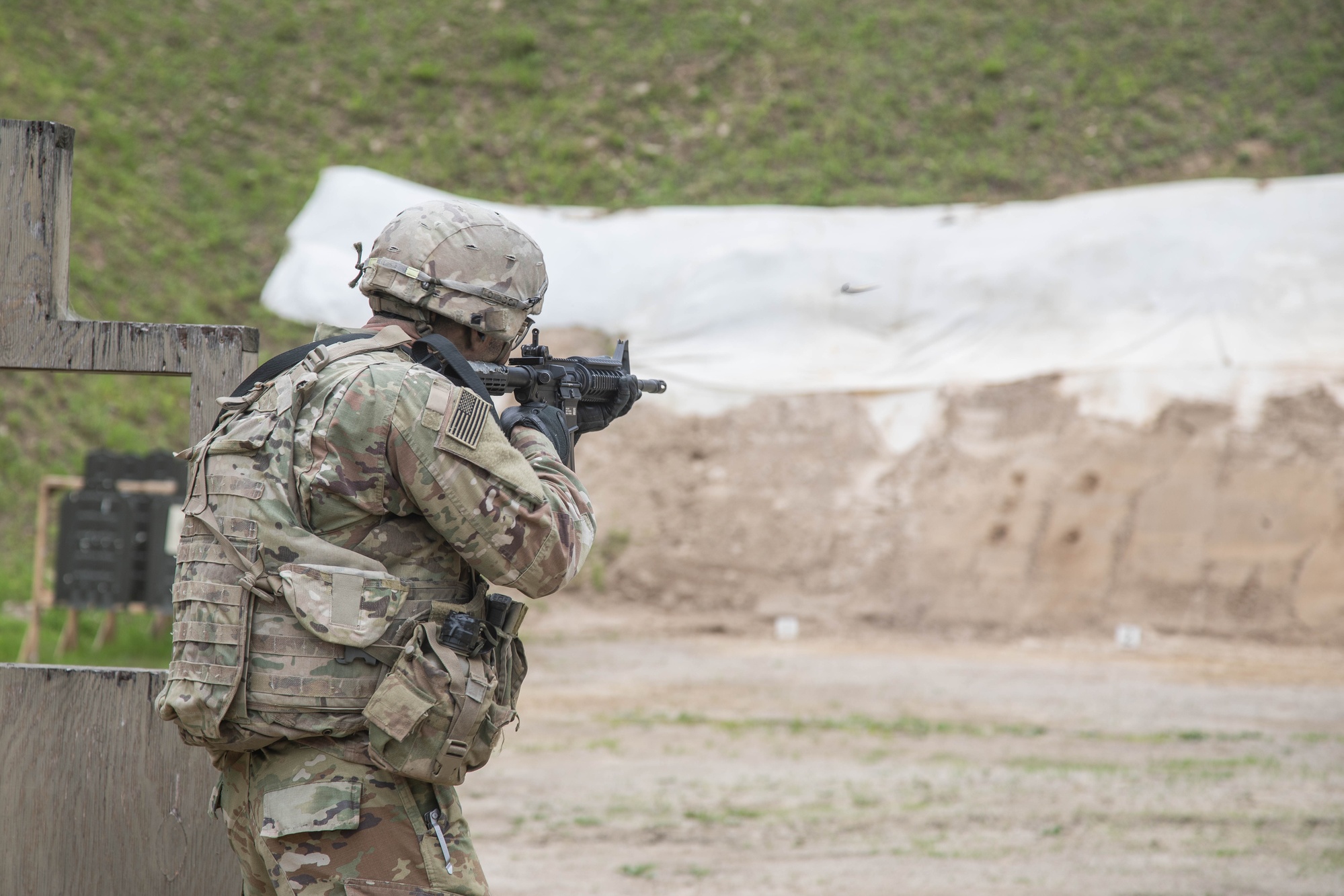 A helmeted soldier viewed from behind aims a rifle at targets on Ingman Range at Camp Casey.